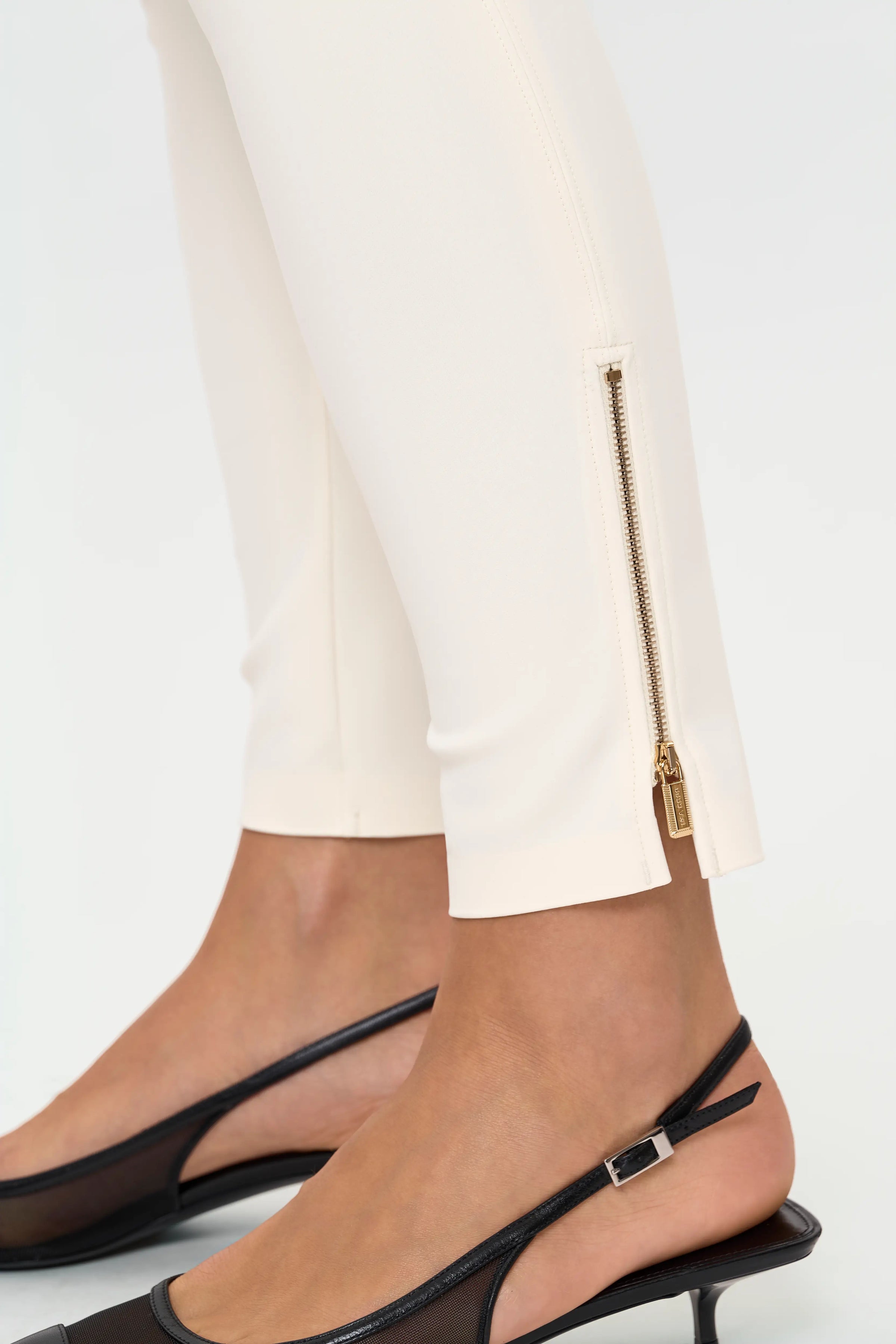 Close-up of CHIARA cajo stretch pants highlighting the gold-tone ankle zipper and smooth stretch fabric