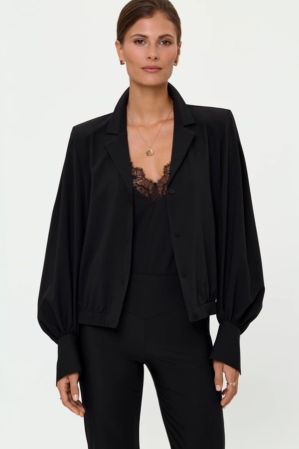 Woman wearing black Venta stretch shirt layered over a black lace camisole with black Larix stretch pants